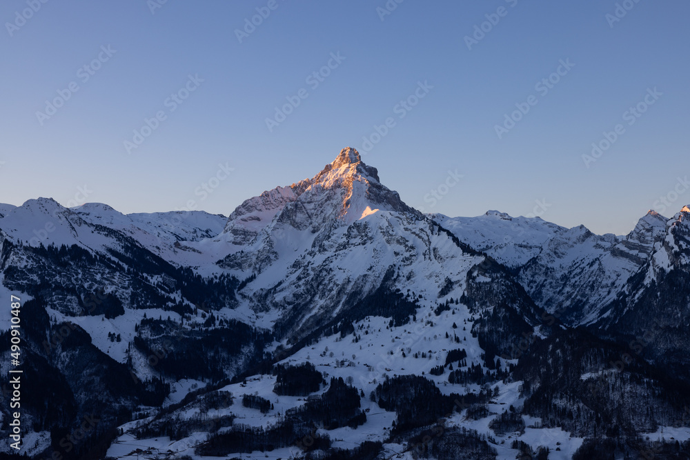 A mountain in the Swiss Alps beautifully set in scene by the morning sun. A majestic sight from a mountain that looks like the Matterhorn.