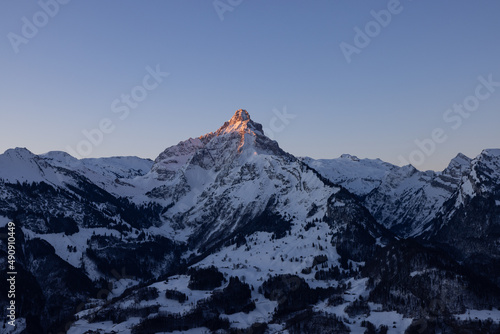 A mountain in the Swiss Alps beautifully set in scene by the morning sun. A majestic sight from a mountain that looks like the Matterhorn.