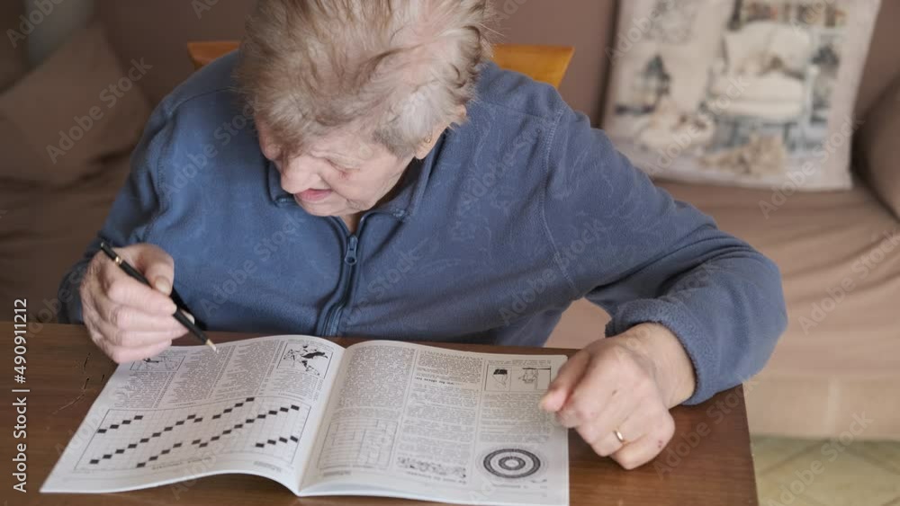 Elderly woman solves crossword puzzle. Senior woman sitting on a sofa with a comforter on her legs playing crossword. Brain and memory training. Enhancing short term memory skills.
Elderly woman solves crossword puzzle. Senior woman sitting on a sofa with a comforter on her legs playing crossword. Brain and memory training. Enhancing short term memory skills.