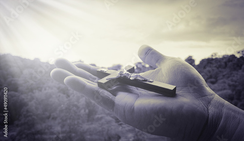 Hand holding Holy Cross with bright shining light. photo