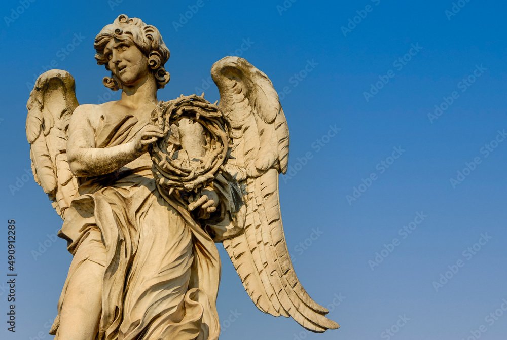 Fototapeta premium Rome, Italy - June 2000: A stone statue of an angel on a blue sky background