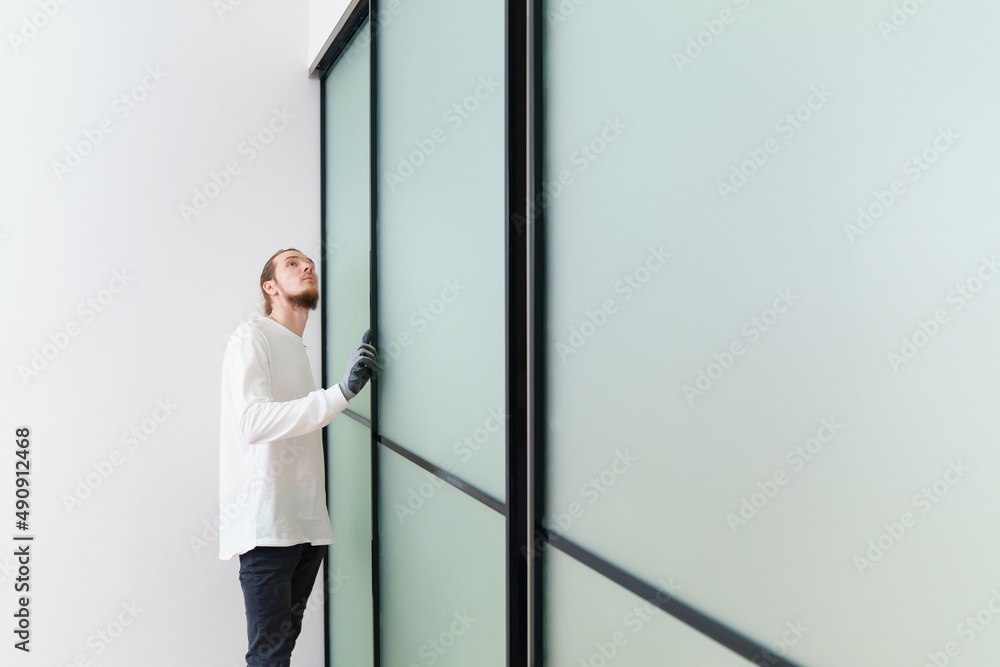 master adjusts sliding doors of wardrobe made of metal and glass. master adjusts sliding doors of wardrobe made of metal and glass.