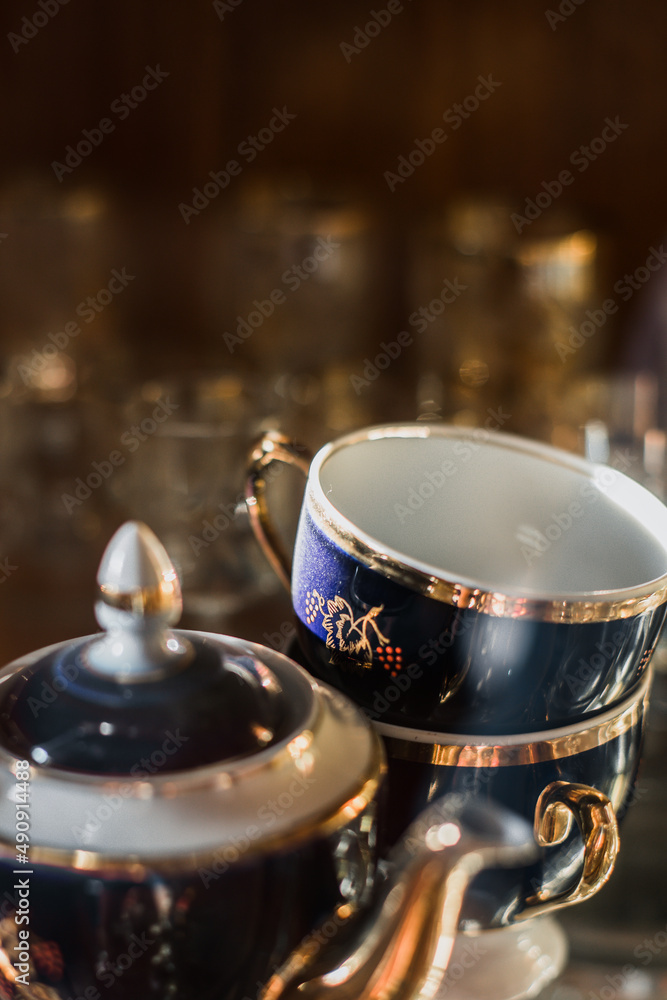Fototapeta premium Antique old service. Old service in a sideboard at a summer cottage. collection of tea porcelain service, cobalt gilding, service behind the flow