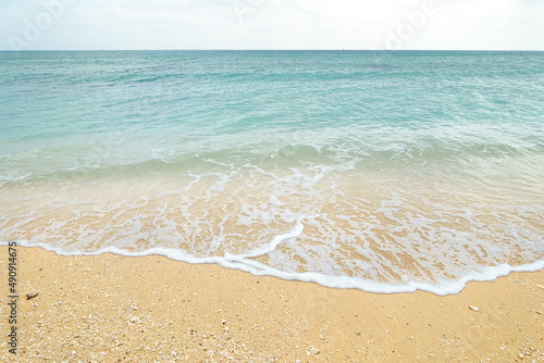 A beach with waves, small shells and finely broken coral