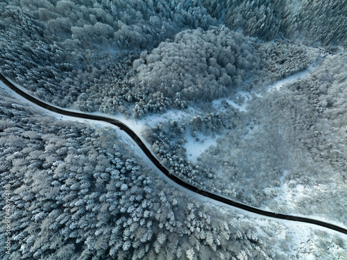 Mountain road in winter shoot from above drone aerial view trees covered in snow © AlexandruPh