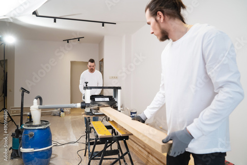 carpenters working with wood on the planing machine