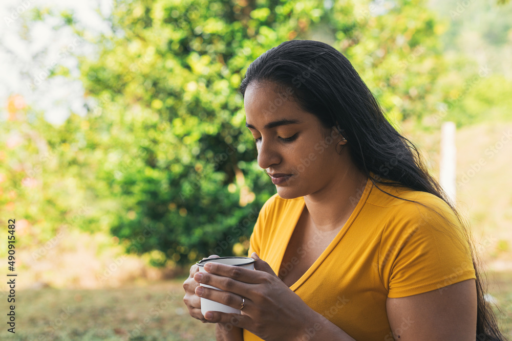 latin woman drinking coffee in a white cup, woman in a natural environment latin woman drinking coffee in a white cup, woman in a natural environment
