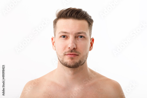 Portrait of a naked young man with stubble on a white background.