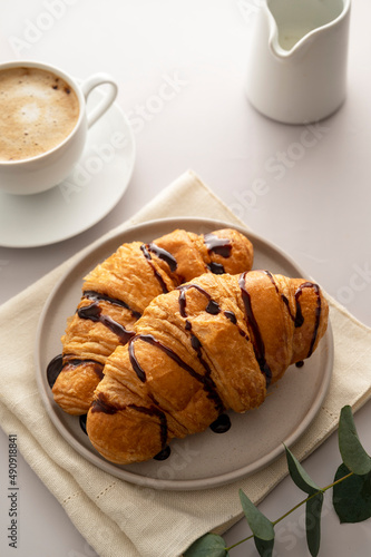 Croissants with chocolate and coffee cup on bright background. Breakfast time