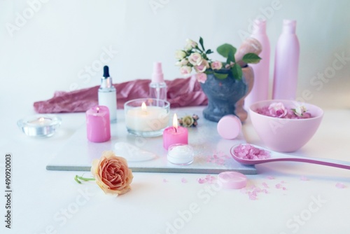 Spa, fresh pink roses, burning candles, oils and tinctures on a light background, healthy lifestyle, relaxation, home cosmetics, aromatherapy, romantic mood, alternative medicine