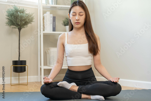 Workout, beautiful asian young woman, girl hand in calm pose sitting practice meditating in lotus position on mat at home, meditation, exercise for wellbeing, healthy care. Relaxation, happy leisure.
