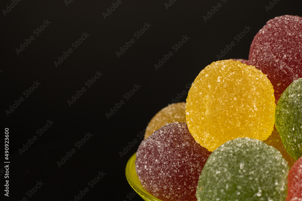 Colored mix sweets marmalade in the saucer on a black background. Fruit jelly yellow red pink green sprinkled with sugar. Cooking concept delicious sweet food. Colored mix sweets marmalade in the saucer on a black background. Fruit jelly yellow red pink green sprinkled with sugar. Cooking concept delicious sweet food.