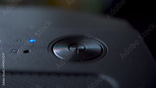 Macro video of a person turning on and off a personal computer with his finger. Technology concept. Turning on a device with a shallow depth of field.