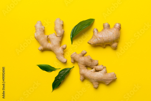 Fototapeta Naklejka Na Ścianę i Meble -  Finely dry Ginger powder in bowl with green leaves isolated on colored background. top view flat lay