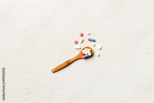 Vitamin capsules in a wooden spoon on a colored background. Pills served as a healthy meal. Drugs, pharmacy, medicine or medical healthycare concept