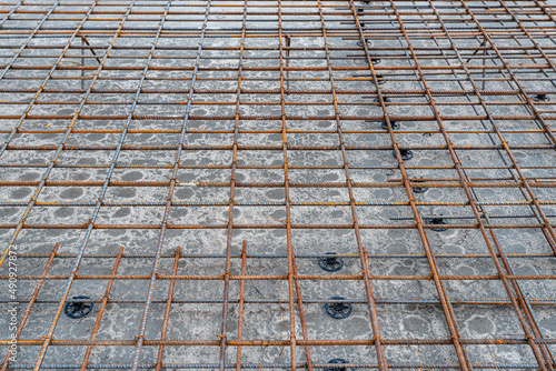 The foundation slab is made of reinforcement rods, bound with tie wire, bonded reinforcement visible up close. photo