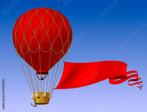 Red air balloon with red banner and wicker basket isolated on blue sky
