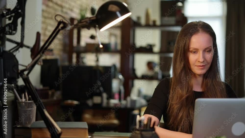 Businesswoman using laptop computer managing small business online in home office. Happy, smiling woman. Confident female entrepreneur. Businesswoman using laptop computer managing small business online in home office. Happy, smiling woman. Confident female entrepreneur.