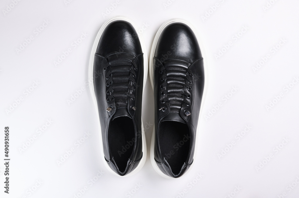 A pair of black sneakers with white soles isolated on a white background. A pair of black sneakers with white soles isolated on a white background.