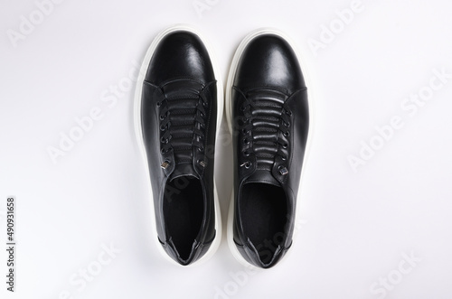 A pair of black sneakers with white soles isolated on a white background.