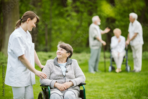 Group of senior patients with caregiver in the garden of nursing home