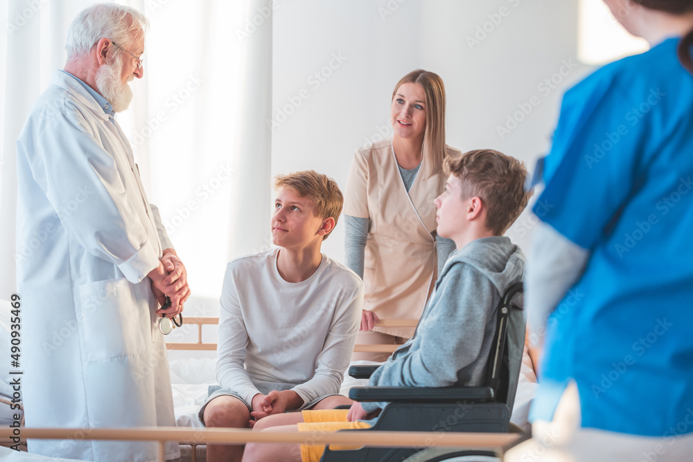 Fototapeta premium Senior grey doctor and female young intern working together at hospital