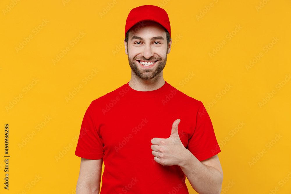 Professional delivery guy employee man in red cap T-shirt uniform workwear work as dealer courier showing thumb up like gesture isolated on plain yellow background studio portrait. Service concept Professional delivery guy employee man in red cap T-shirt uniform workwear work as dealer courier showing thumb up like gesture isolated on plain yellow background studio portrait. Service concept