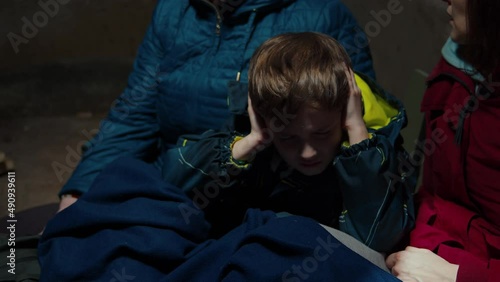 A scared child hiding in the basement with his family