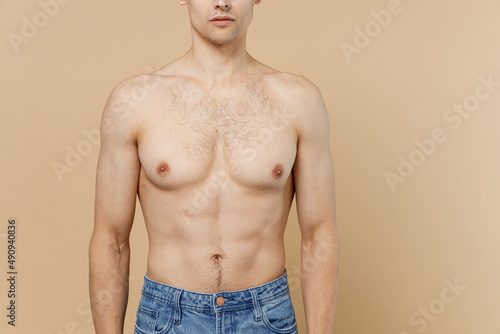 Young caucasian european man 20s wear jeans pants with naked torso isolated on pastel pastel beige color background studio portrait. Body care healthcare fitness sport bodybuilding lifestyle concept. photo