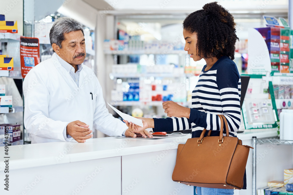 I need the following medication please. Shot of a pharmacist assisting a young woman in a chemist.