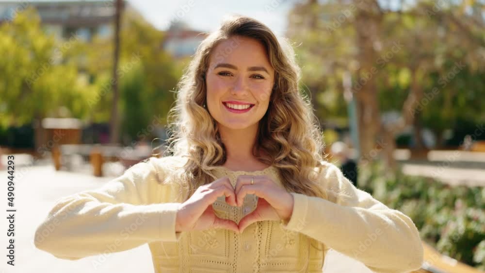 Young blonde woman smiling confident doing heart gesture with hands at park Young blonde woman smiling confident doing heart gesture with hands at park