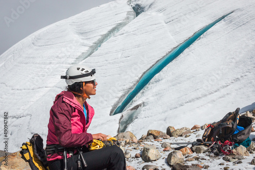 Beautiful latin woman smiling naturally while hiking in front of crevasse (crack) in a glacier