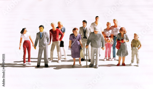 Group of mixed people, old and young, standing in a line or queue symbolized by small figurines photo