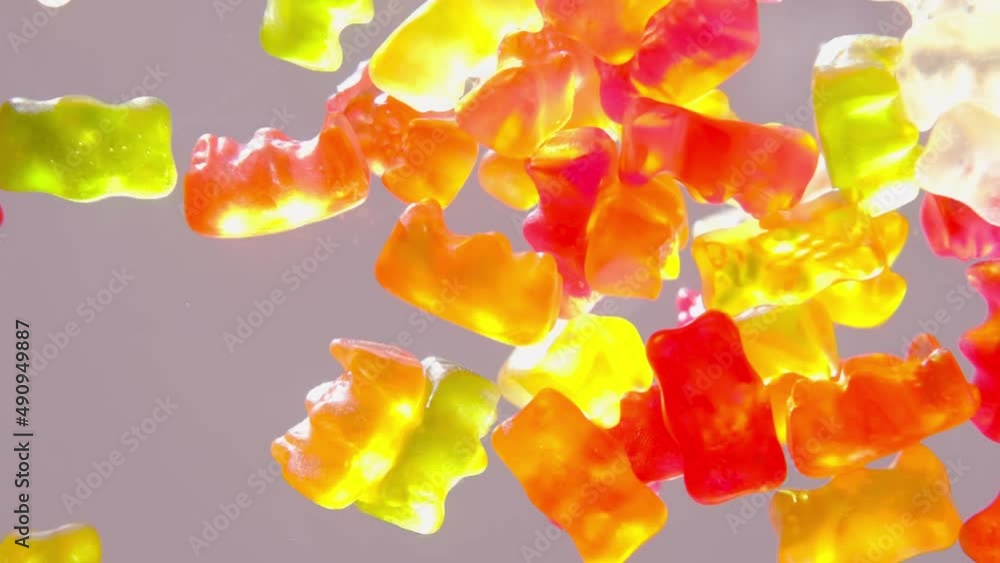 red, orange, yellow gelatin candies, drugfilled gelatin bears falling on the table from above