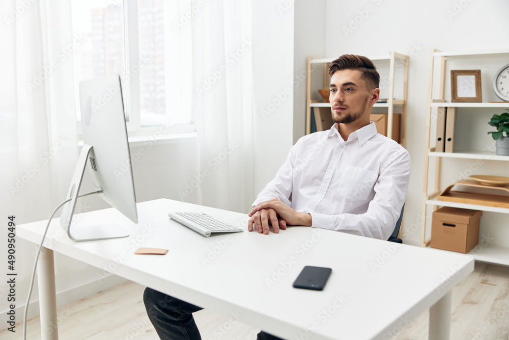 handsome man sitting at a desk in front of a computer with a keyboard technologies handsome man sitting at a desk in front of a computer with a keyboard technologies