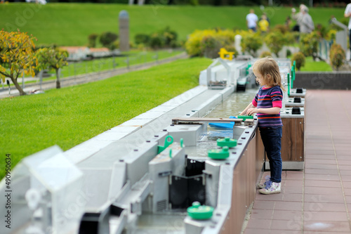 Little girl playing water dam simulation at Madurodam miniature park, The Hague, Netherlands