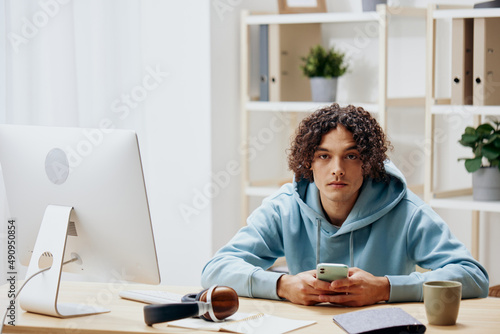 handsome guy in a blue jacket in front of a computer with phone technologies