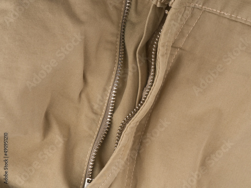 The unbuttoned fly of light trousers. Closeup