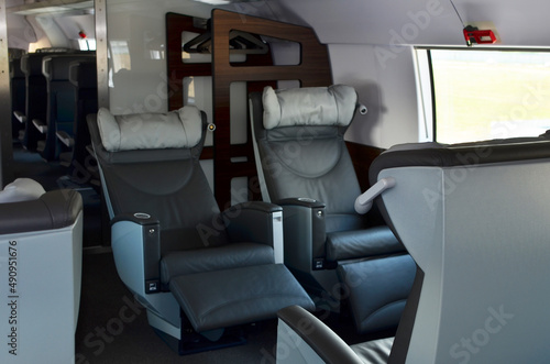 Seats in the cabin of business class carriage of a passenger high speed train. Modern interior of the urban railway transport. Leather armchair seat on a european double-decker passenger train.