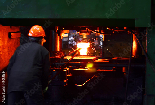 Fotografie Blacksmith work with red hot iron under a press on metallurgical plant