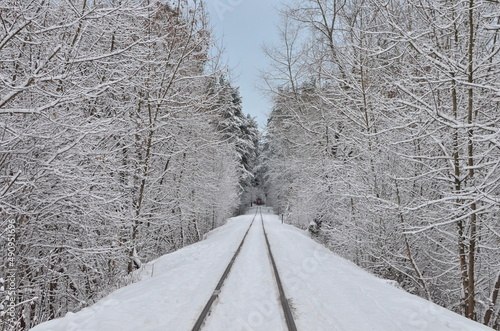 Railroad in the snow. Winter landscape in the forest with an empty railroad after a snowfall. Narrow gauge railroad in winter.