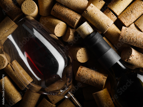 Luxurious composition. A bottle of fine red wine and a wine glass lie on the corks. There are no people in the photo. Romance, celebration, restaurant, hotel, winemaking. wine tasting, banquet.