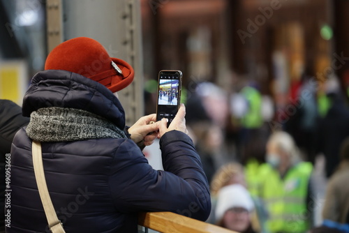 Starsza pani w czerwonym kapeluszu ze smartfonem robi zdjęcie.