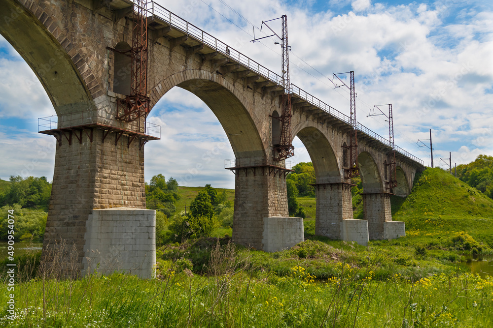 Viaduct. Beautiful old arched stone railway bridge against the backdrop of a scenic landscape