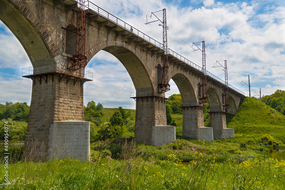 Viaduct. Beautiful old arched stone railway bridge against the backdrop of a scenic landscape Viaduct. Beautiful old arched stone railway bridge against the backdrop of a scenic landscape