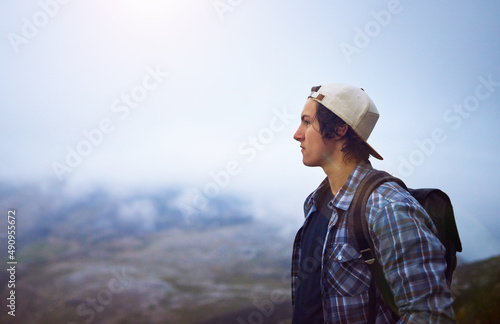 Make your life an adventure. Shot of a young hiker admiring a foggy view from the top of a mountain. © Ruan J/peopleimages.com