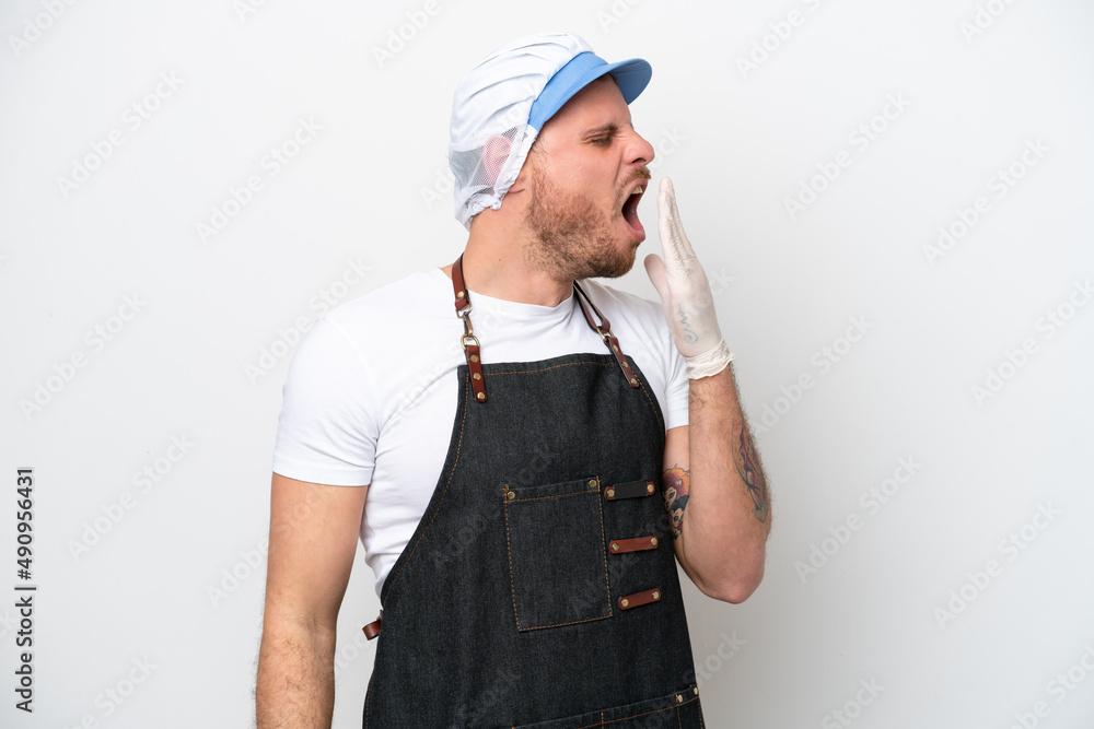 Fishmonger man wearing an apron isolated on white background yawning and covering wide open mouth with hand Fishmonger man wearing an apron isolated on white background yawning and covering wide open mouth with hand