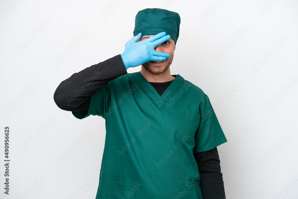 Surgeon Brazilian man in green uniform isolated on white background covering eyes by hands and smiling Surgeon Brazilian man in green uniform isolated on white background covering eyes by hands and smiling