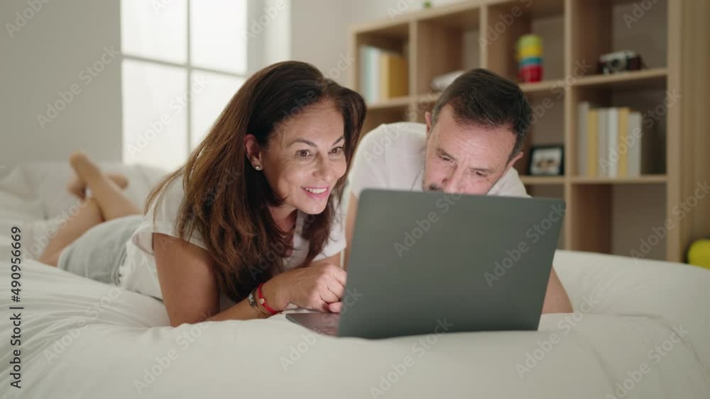 Man and woman couple using laptop lying on bed at bedroom Man and woman couple using laptop lying on bed at bedroom