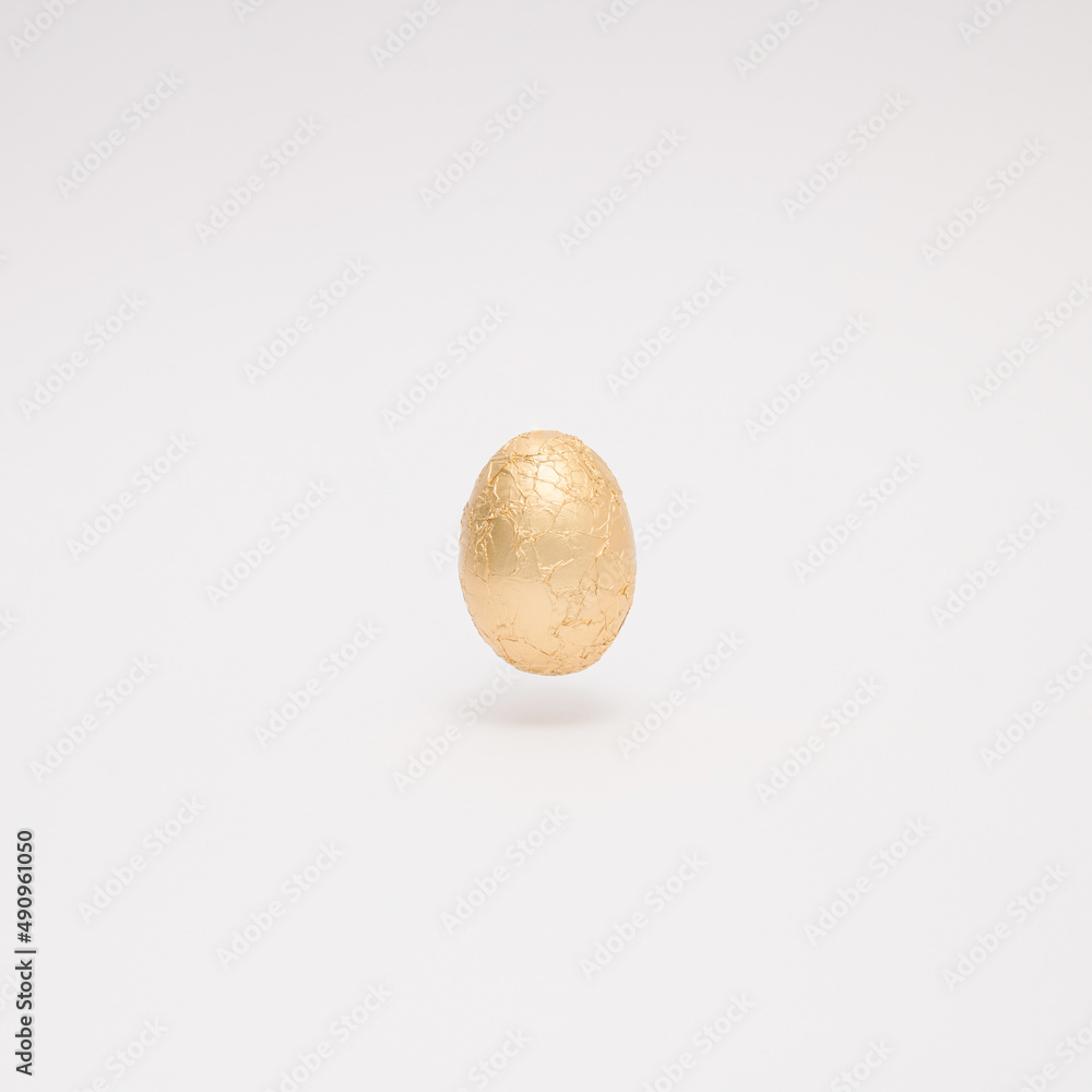 Easter creative layout made with golden Easter egg levitating on a white background. Minimal holiday still life concept. Easter creative layout made with golden Easter egg levitating on a white background. Minimal holiday still life concept.